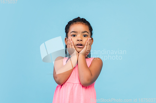 Image of Happy longhair brunette little girl isolated on blue studio background. Looks happy, cheerful, sincere. Copyspace. Childhood, education, emotions concept