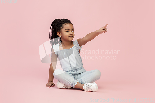 Image of Happy longhair brunette little girl isolated on pink studio background. Looks happy, cheerful, sincere. Copyspace. Childhood, education, emotions concept