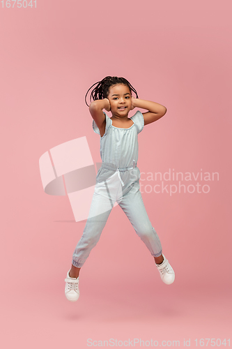 Image of Happy longhair brunette little girl isolated on pink studio background. Looks happy, cheerful, sincere. Copyspace. Childhood, education, emotions concept