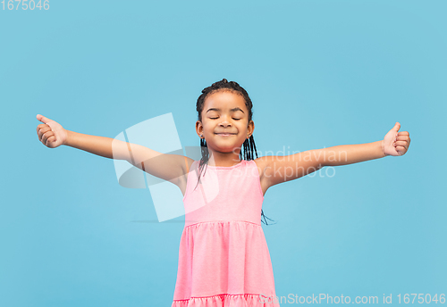 Image of Happy longhair brunette little girl isolated on blue studio background. Looks happy, cheerful, sincere. Copyspace. Childhood, education, emotions concept