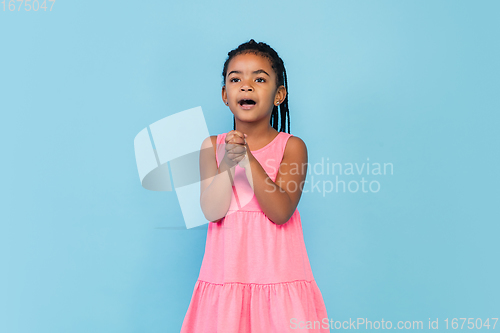 Image of Happy longhair brunette little girl isolated on blue studio background. Looks happy, cheerful, sincere. Copyspace. Childhood, education, emotions concept