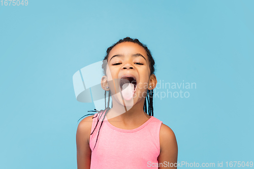 Image of Happy longhair brunette little girl isolated on blue studio background. Looks happy, cheerful, sincere. Copyspace. Childhood, education, emotions concept