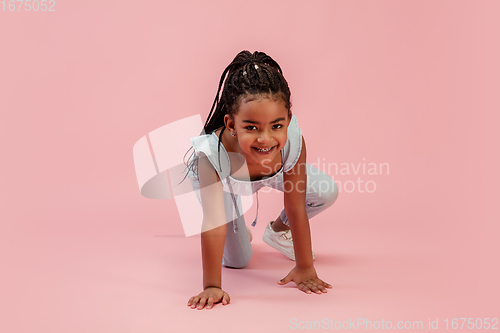 Image of Happy longhair brunette little girl isolated on pink studio background. Looks happy, cheerful, sincere. Copyspace. Childhood, education, emotions concept