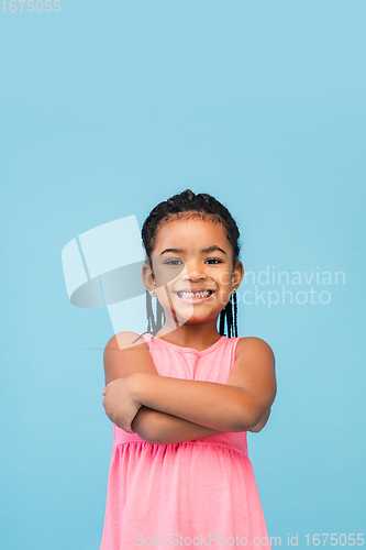 Image of Happy longhair brunette little girl isolated on blue studio background. Looks happy, cheerful, sincere. Copyspace. Childhood, education, emotions concept