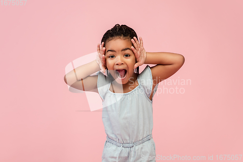 Image of Happy longhair brunette little girl isolated on pink studio background. Looks happy, cheerful, sincere. Copyspace. Childhood, education, emotions concept