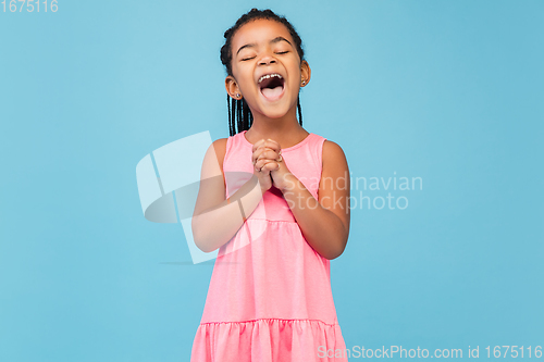 Image of Happy longhair brunette little girl isolated on blue studio background. Looks happy, cheerful, sincere. Copyspace. Childhood, education, emotions concept