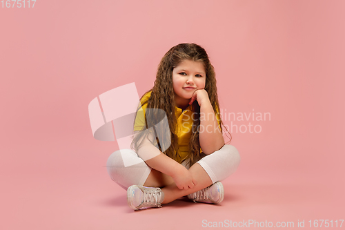 Image of Happy caucasian little girl isolated on studio background. Looks happy, cheerful, sincere. Copyspace. Childhood, education, emotions concept