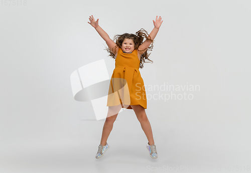 Image of Happy caucasian little girl isolated on studio background. Looks happy, cheerful, sincere. Copyspace. Childhood, education, emotions concept