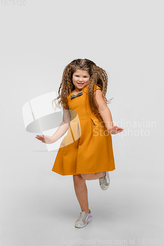 Image of Happy caucasian little girl isolated on studio background. Looks happy, cheerful, sincere. Copyspace. Childhood, education, emotions concept