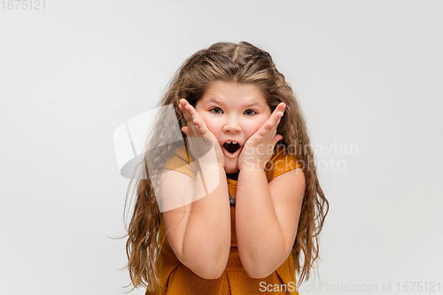 Image of Happy caucasian little girl isolated on studio background. Looks happy, cheerful, sincere. Copyspace. Childhood, education, emotions concept