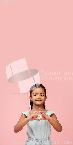 Image of Happy longhair brunette little girl isolated on pink studio background. Looks happy, cheerful, sincere. Copyspace. Childhood, education, emotions concept