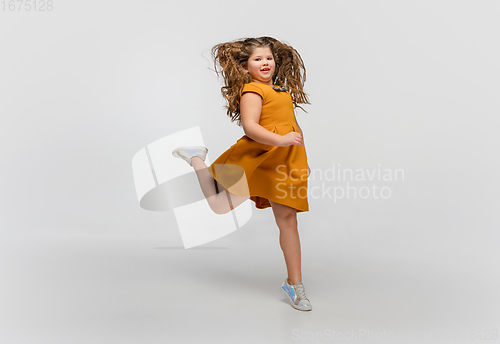 Image of Happy caucasian little girl isolated on studio background. Looks happy, cheerful, sincere. Copyspace. Childhood, education, emotions concept