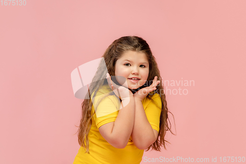 Image of Happy caucasian little girl isolated on studio background. Looks happy, cheerful, sincere. Copyspace. Childhood, education, emotions concept