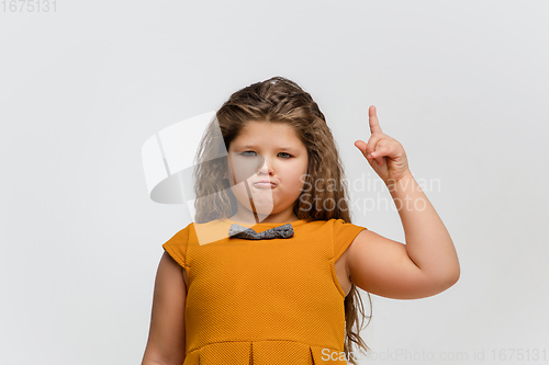 Image of Happy caucasian little girl isolated on studio background. Looks happy, cheerful, sincere. Copyspace. Childhood, education, emotions concept