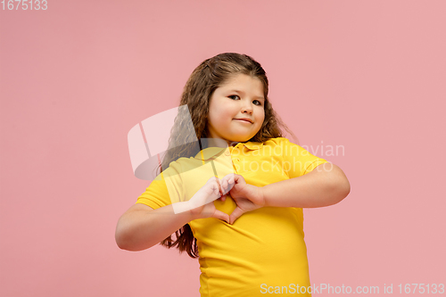 Image of Happy caucasian little girl isolated on studio background. Looks happy, cheerful, sincere. Copyspace. Childhood, education, emotions concept