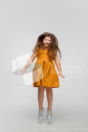 Image of Happy caucasian little girl isolated on studio background. Looks happy, cheerful, sincere. Copyspace. Childhood, education, emotions concept