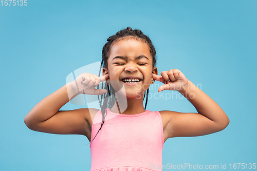 Image of Happy longhair brunette little girl isolated on blue studio background. Looks happy, cheerful, sincere. Copyspace. Childhood, education, emotions concept