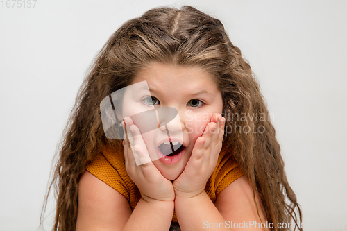 Image of Happy caucasian little girl isolated on studio background. Looks happy, cheerful, sincere. Copyspace. Childhood, education, emotions concept