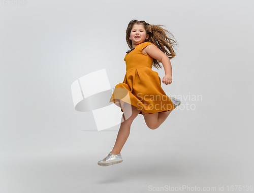 Image of Happy caucasian little girl isolated on studio background. Looks happy, cheerful, sincere. Copyspace. Childhood, education, emotions concept