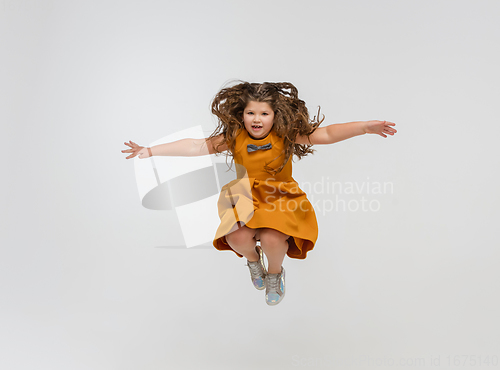 Image of Happy caucasian little girl isolated on studio background. Looks happy, cheerful, sincere. Copyspace. Childhood, education, emotions concept