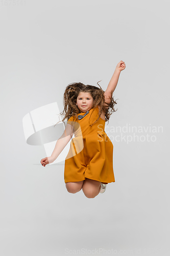 Image of Happy caucasian little girl isolated on studio background. Looks happy, cheerful, sincere. Copyspace. Childhood, education, emotions concept