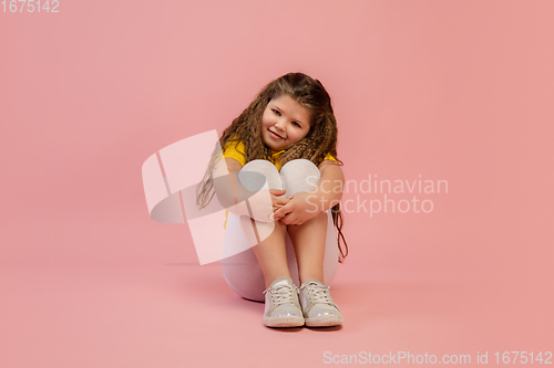 Image of Happy caucasian little girl isolated on studio background. Looks happy, cheerful, sincere. Copyspace. Childhood, education, emotions concept