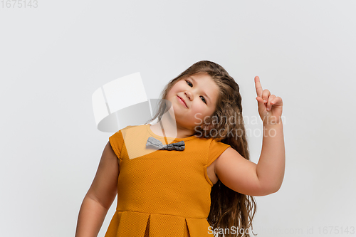 Image of Happy caucasian little girl isolated on studio background. Looks happy, cheerful, sincere. Copyspace. Childhood, education, emotions concept