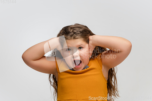 Image of Happy caucasian little girl isolated on studio background. Looks happy, cheerful, sincere. Copyspace. Childhood, education, emotions concept