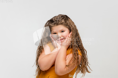 Image of Happy caucasian little girl isolated on studio background. Looks happy, cheerful, sincere. Copyspace. Childhood, education, emotions concept