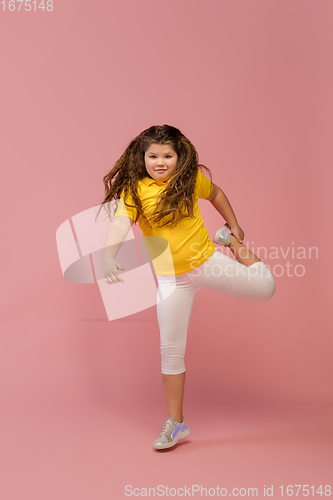 Image of Happy caucasian little girl isolated on studio background. Looks happy, cheerful, sincere. Copyspace. Childhood, education, emotions concept