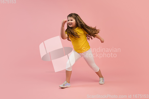 Image of Happy caucasian little girl isolated on studio background. Looks happy, cheerful, sincere. Copyspace. Childhood, education, emotions concept