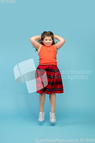 Image of Happy caucasian little girl isolated on studio background. Looks happy, cheerful, sincere. Copyspace. Childhood, education, emotions concept