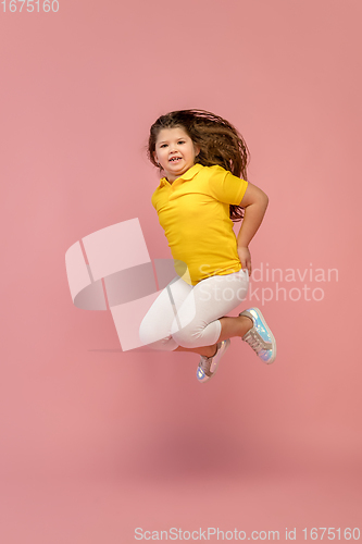 Image of Happy caucasian little girl isolated on studio background. Looks happy, cheerful, sincere. Copyspace. Childhood, education, emotions concept