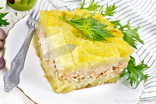 Image of Casserole with potatoes and fish in plate on light wooden board