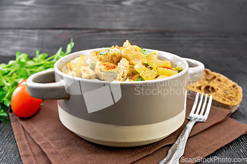 Image of Chicken with vegetables and peas in saucepan on wooden board