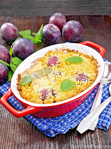 Image of Crumble with plum in brazier on wooden board