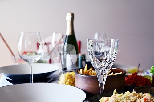 Image of bottle of wine, empty wineglasses and side dishes on the table