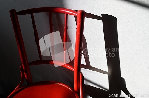 Image of red ancient chair and its shadow on the wall