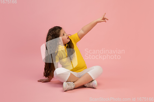 Image of Happy caucasian little girl isolated on studio background. Looks happy, cheerful, sincere. Copyspace. Childhood, education, emotions concept