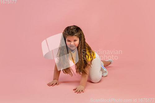 Image of Happy caucasian little girl isolated on studio background. Looks happy, cheerful, sincere. Copyspace. Childhood, education, emotions concept