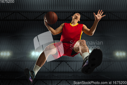 Image of Young professional basketball player in action, motion isolated on black background, look from the bottom. Concept of sport, movement, energy and dynamic.