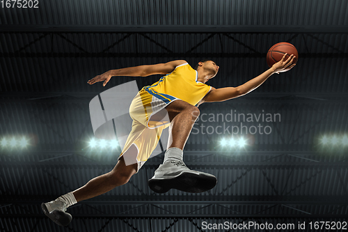 Image of Young professional basketball player in action, motion isolated on black background, look from the bottom. Concept of sport, movement, energy and dynamic.