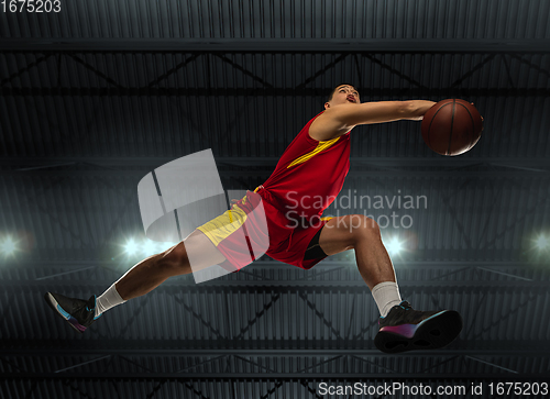 Image of Young professional basketball player in action, motion isolated on black background, look from the bottom. Concept of sport, movement, energy and dynamic.