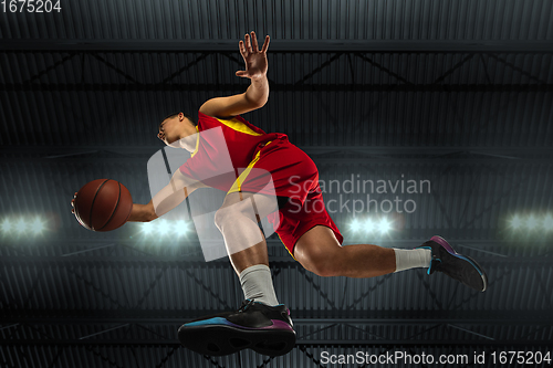 Image of Young professional basketball player in action, motion isolated on black background, look from the bottom. Concept of sport, movement, energy and dynamic.