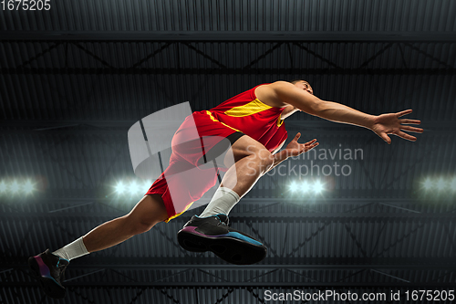 Image of Young professional basketball player in action, motion isolated on black background, look from the bottom. Concept of sport, movement, energy and dynamic.