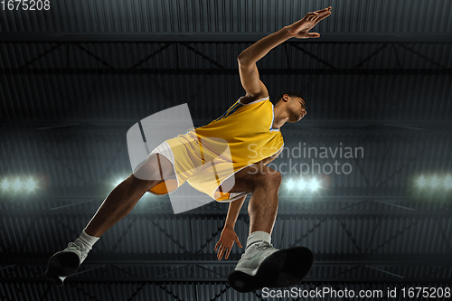 Image of Young professional basketball player in action, motion isolated on black background, look from the bottom. Concept of sport, movement, energy and dynamic.