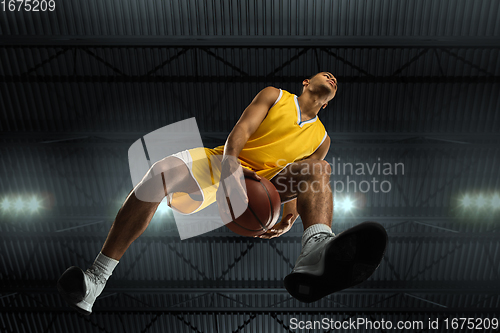 Image of Young professional basketball player in action, motion isolated on black background, look from the bottom. Concept of sport, movement, energy and dynamic.