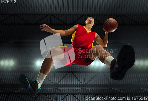 Image of Young professional basketball player in action, motion isolated on black background, look from the bottom. Concept of sport, movement, energy and dynamic.