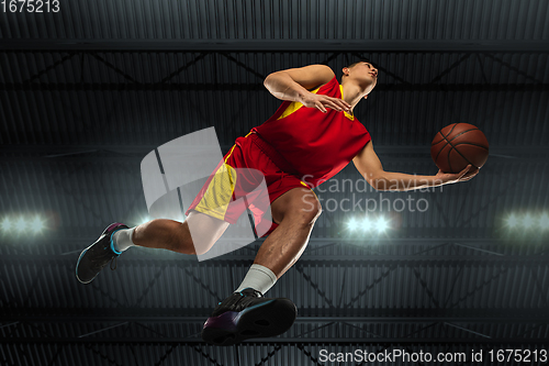 Image of Young professional basketball player in action, motion isolated on black background, look from the bottom. Concept of sport, movement, energy and dynamic.