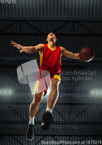 Image of Young professional basketball player in action, motion isolated on black background, look from the bottom. Concept of sport, movement, energy and dynamic.